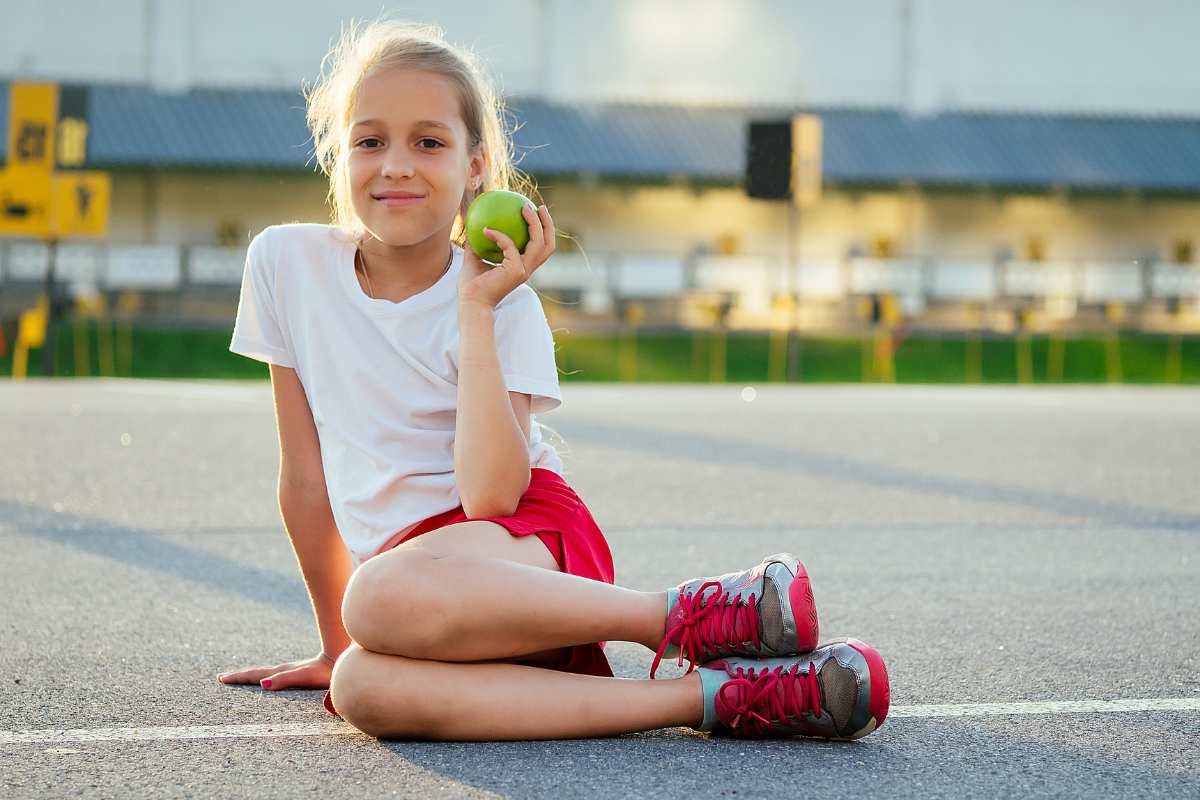 A young athlete holding an apple in Texas.