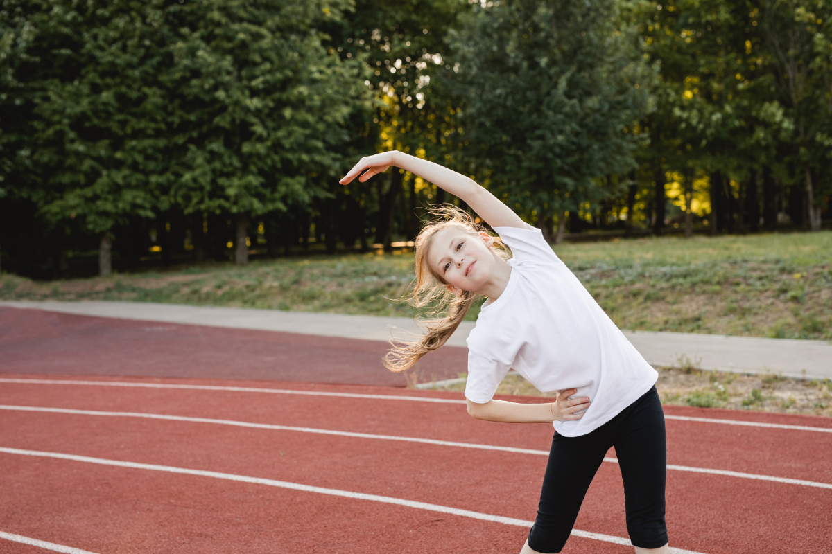 A young girl doing stretches as part of her warm-up routine before running to prevent injury in Austin, Texas.